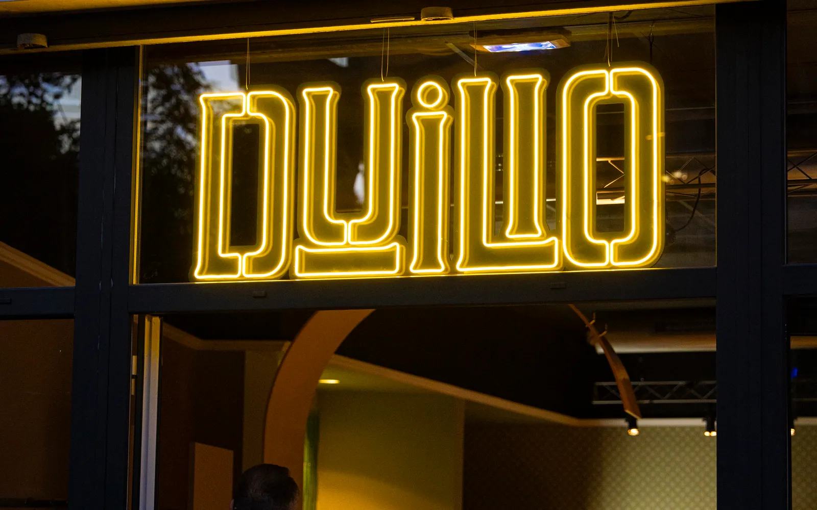 L'insegna al neon gialla di Duilio accesa sull'ingresso del locale